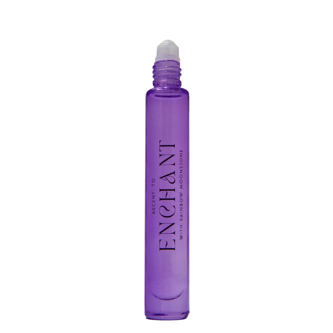 A sleek cylindrical perfume bottle from ASCENTION BEAUTY CO, featuring a roller applicator and adorned with the label "*NEW* Ascent to Enchant With Rainbow Moonstone Perfume" in an elegant font. The captivating purple hue of the bottle complements its mystical allure, while the gleaming Rainbow Moonstone on the label adds a touch of magic. Set against a plain white background, this enchanting fragrance makes a striking impression.