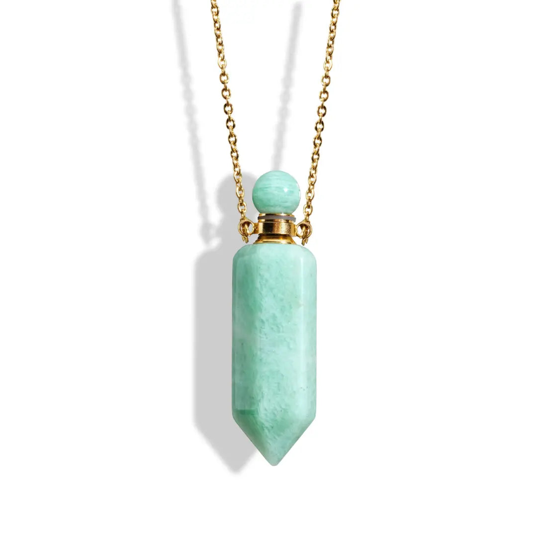 The Crystal Perfume Amulet Necklace (Reward) by Ascention Beauty - Wellness Clean Cruelty-Free Vegan Perfume showcases a smooth, turquoise-colored stone with a pointed end, elegantly hanging from an 18K gold-plated chain. Both the cap and chain are gold, while the natural crystal stone's glossy finish is strikingly highlighted against a white background.