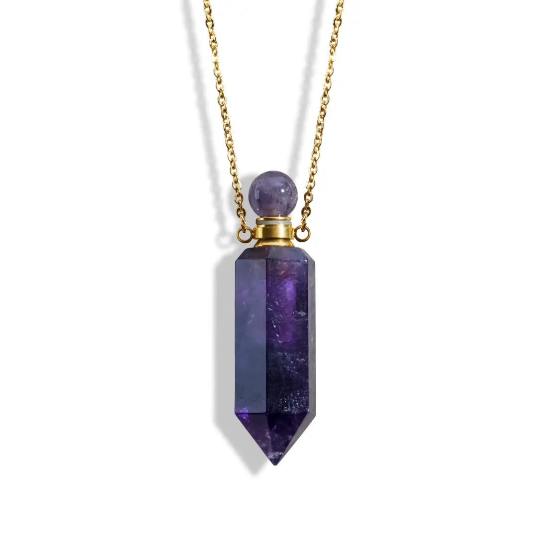 Introducing the Crystal Perfume Amulet Necklace (Reward) by Ascention Beauty, a stunning piece that combines wellness with elegance. This necklace boasts a natural deep purple crystal pendant in a sleek cylindrical shape, topped with a polished stone and beautifully suspended from an 18K gold-plated chain. Crafted by Ascention Beauty, the necklace embraces a clean, cruelty-free, and vegan approach to beauty.